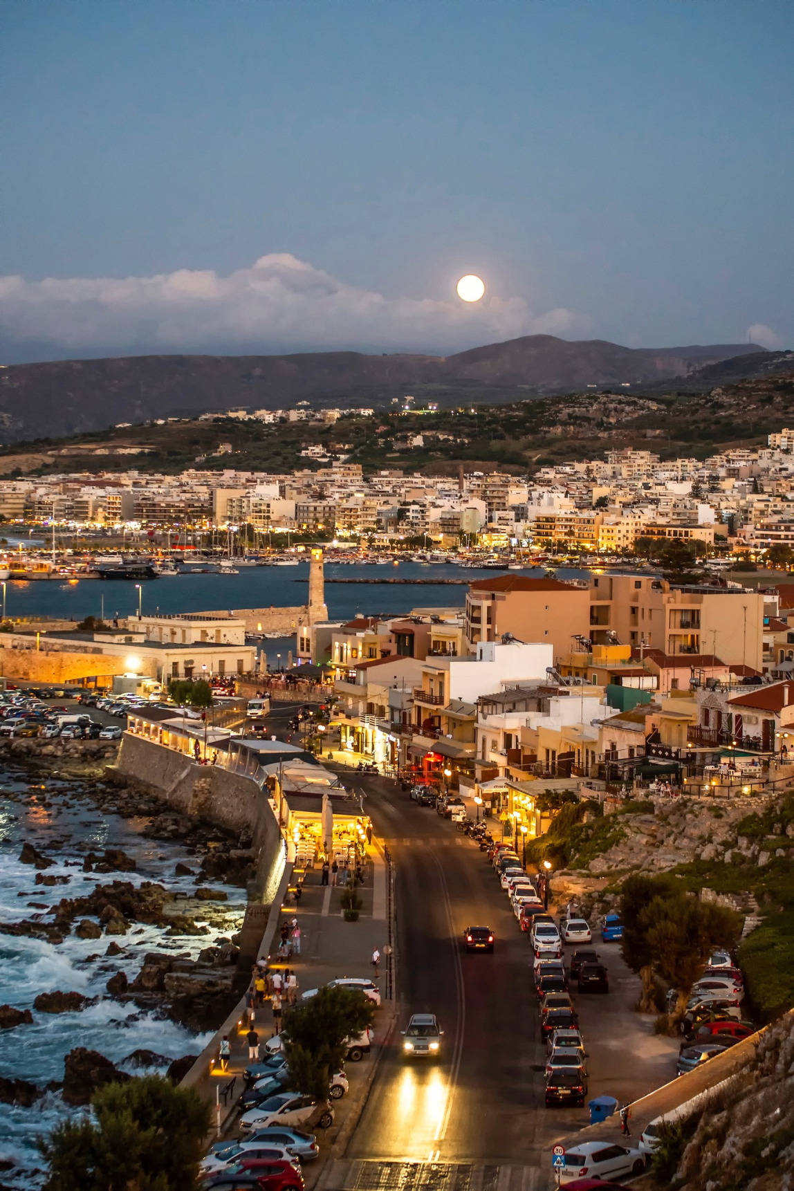 Panoramic night view of the city of Rethymno from Fortezza, with the Venetian harbor and lighthouse under the light of the full moon.