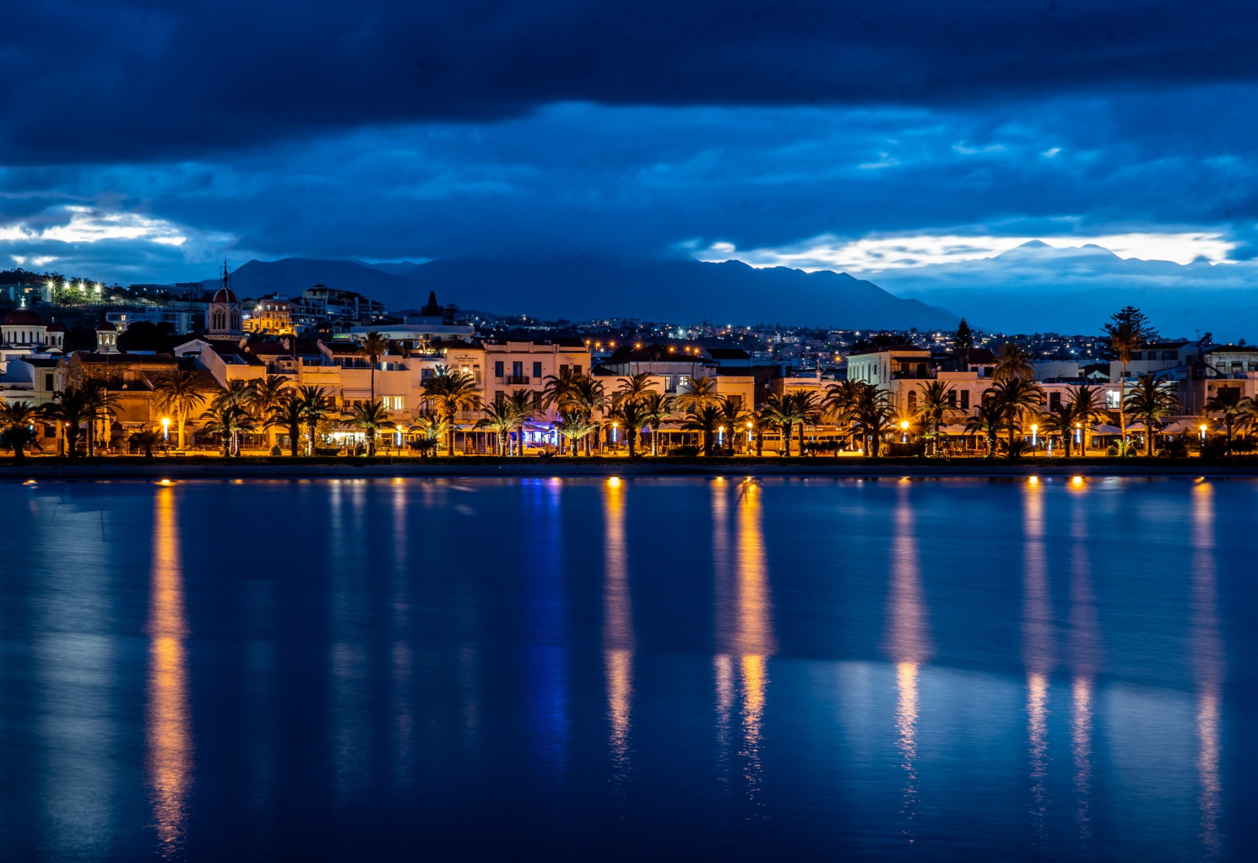 Rethymno Beach at sunset with palm trees, sandy shore, and sea in Crete Greece